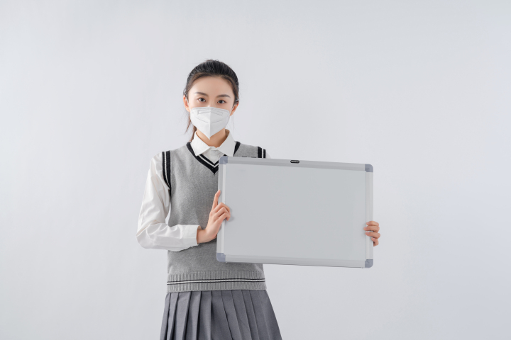戴口罩向镜头展示白板的女生高清图版权图片下载