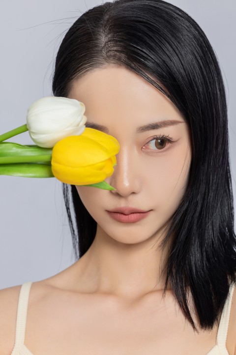 女性手拿黄色郁金香遮挡眼部实拍图版权图片下载