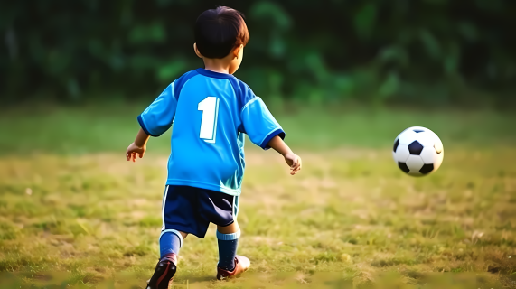 男孩穿蓝色足球衣玩足球摄影图片