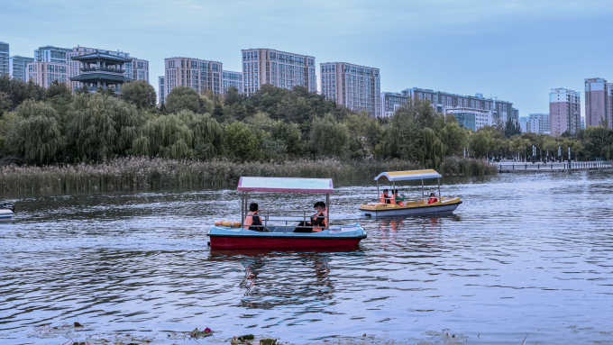 湖面游船娱乐城市高楼实拍图