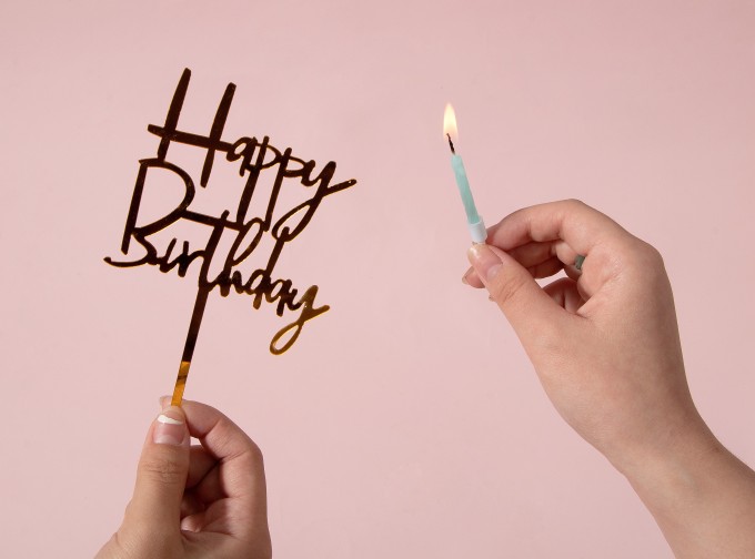 手拿生日快乐插牌燃烧的蜡烛高清图
