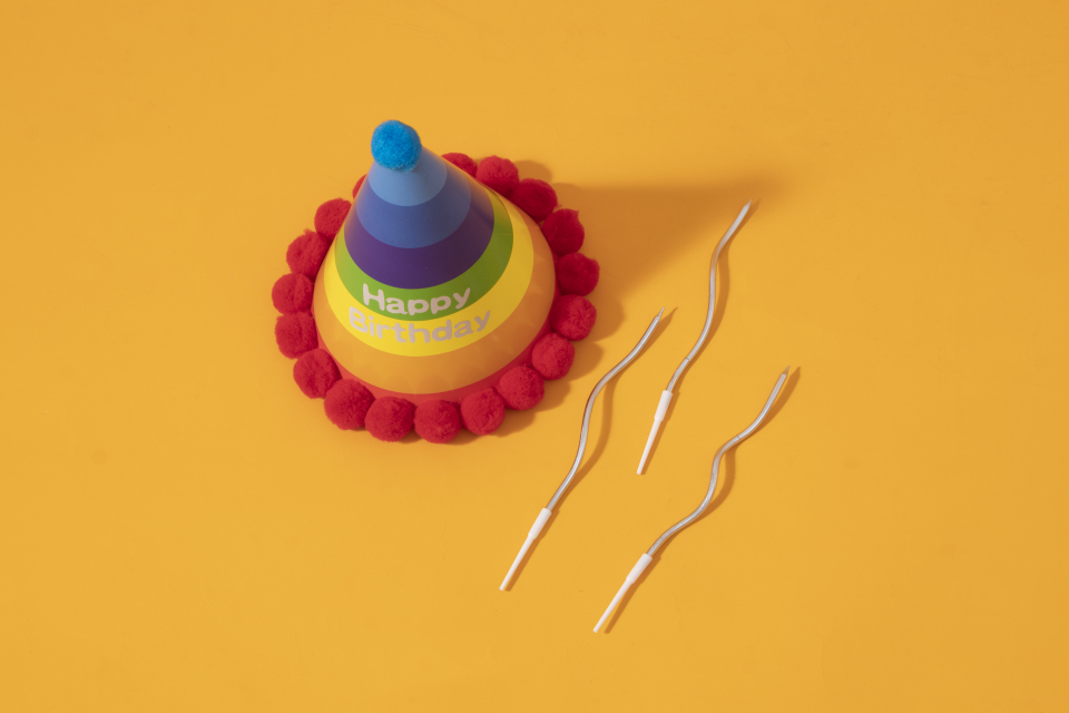 黄色背景生日装饰帽螺旋式蜡烛高清图