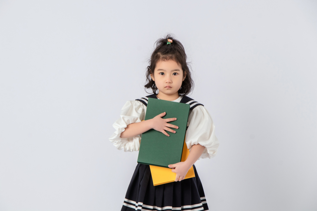 短发卷毛女孩抱厚厚图书实拍图版权图片下载