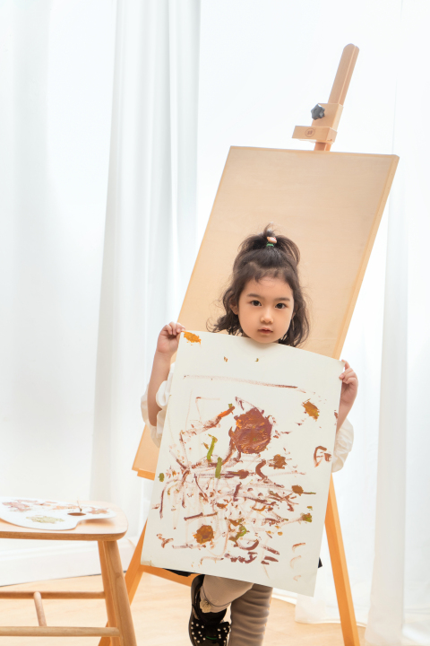 画板前小女孩展示绘画作品版权图片下载