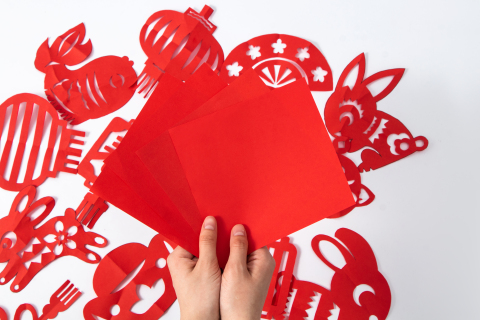 手拿春节喜庆红色彩纸剪纸材料实拍图