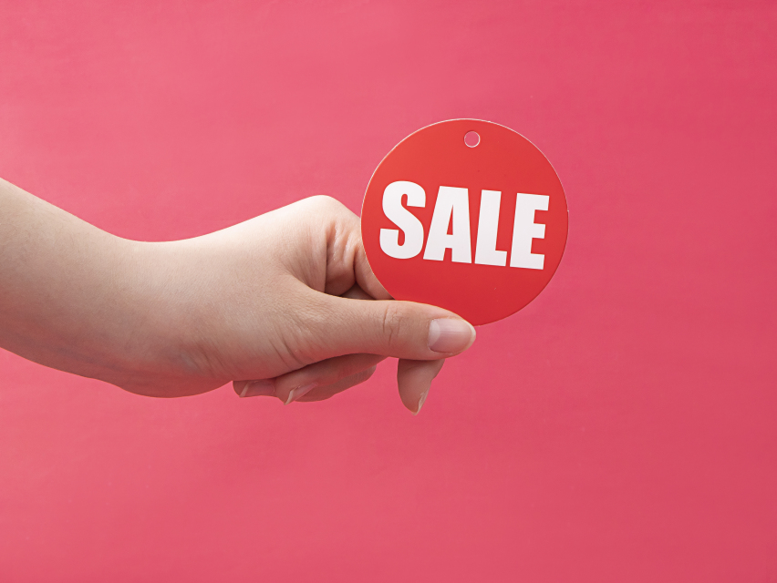 手拿红色圆形促销标签实拍图