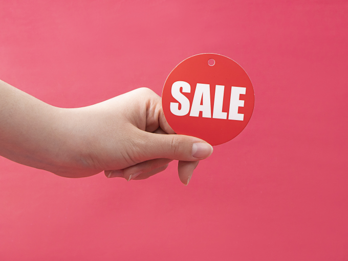 手拿红色圆形促销标签实拍图