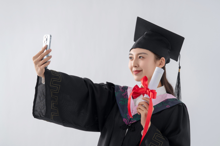 拿着毕业证书用手机自拍的女学生高清图版权图片下载
