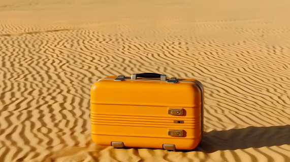 黄沙漠中的黄色行李箱摄影图片