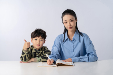 穿衬衣的妈妈陪孩子学习高清图