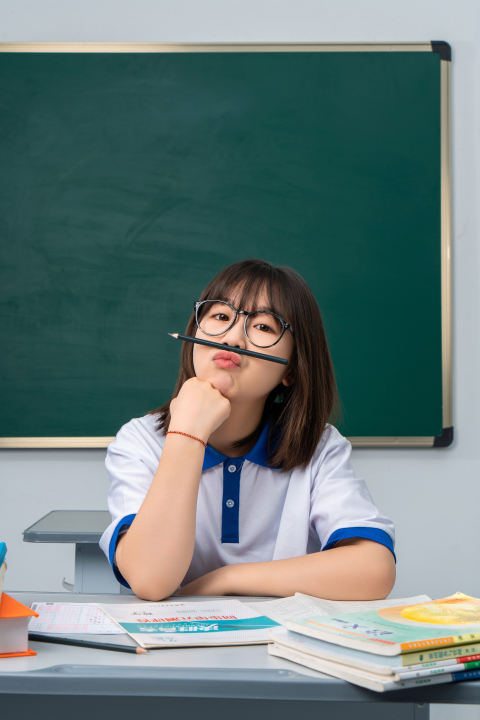 把笔放在鼻子上的女生高清图版权图片下载