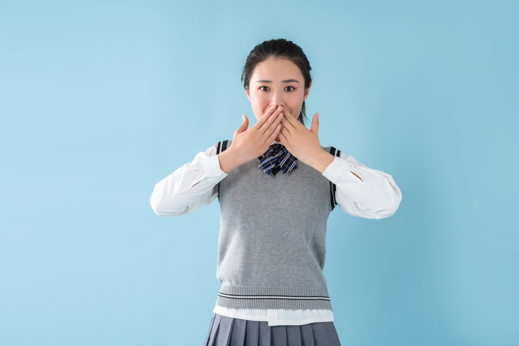 双手放在嘴巴上的女同学高清图版权图片下载
