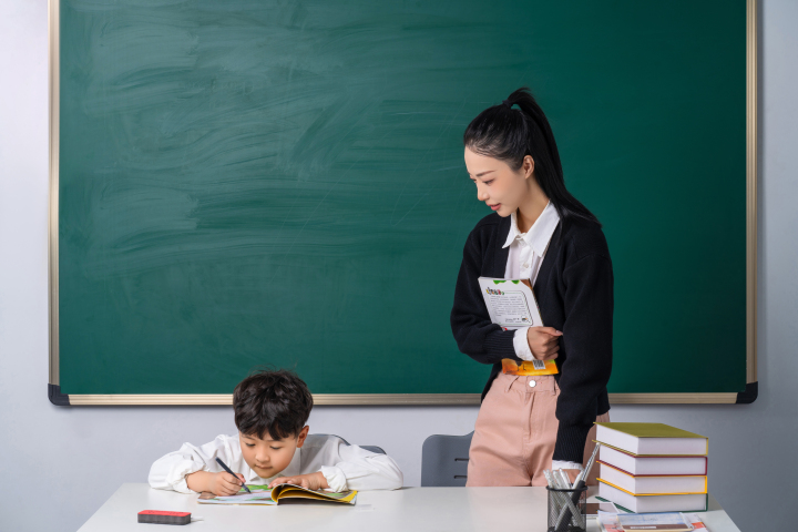 绑着马尾的女老师看着学生写作业高清图版权图片下载