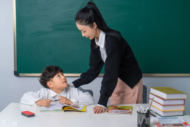 俯身低头看着学生的女老师高清图