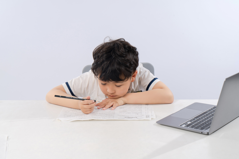 趴着写作业的小男孩高清图