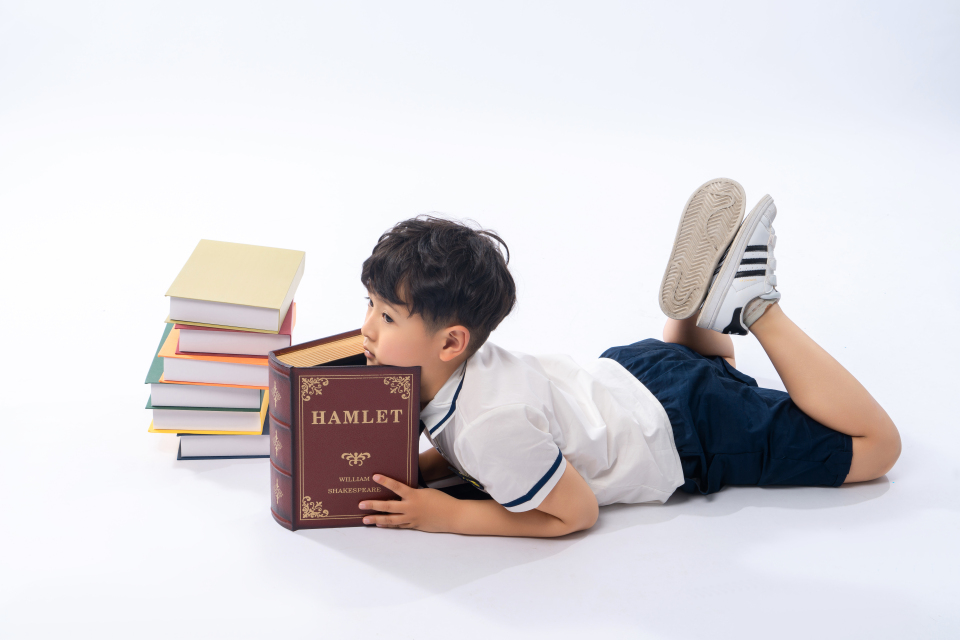 趴在书堆上的小男孩高清图