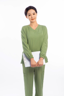 绿色手术服女医生双手拿资料微笑实拍图