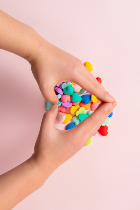 色彩缤纷的糖果上方手比爱心摄影图版权图片下载