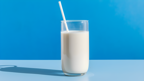 蓝桌上的两根吸管玻璃杯牛奶摄影图片
