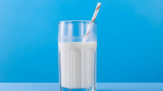 蓝色桌子上的两根吸管的牛奶玻璃杯摄影图片