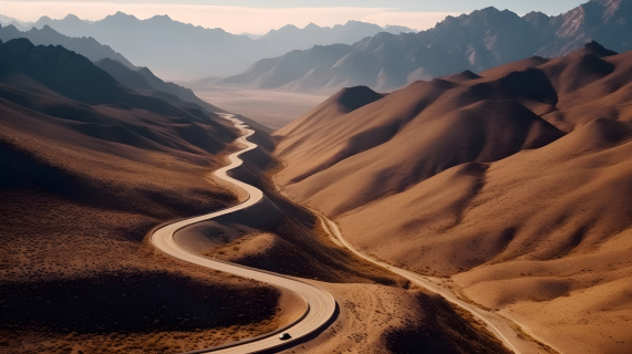 沙漠山脉旁蜿蜒曲折的公路摄影图