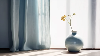 浅蓝色窗帘旁的蓝色花瓶摄影图片