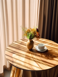 餐厅木质圆桌上的咖啡杯阳光下的极简静物摄影图